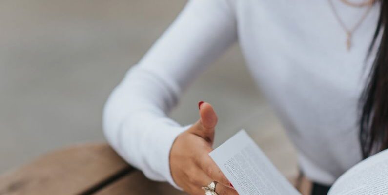 Flip Turn - Serious woman reading book at table in street cafe