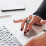 Tapering Strategies - Crop female using touchpad on laptop in office