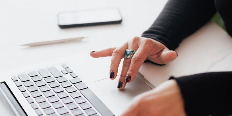 Tapering Strategies - Crop female using touchpad on laptop in office