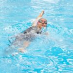 Backstroke - A woman swimming in a pool with a red line