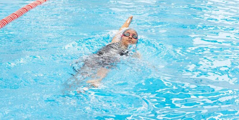 Backstroke - A woman swimming in a pool with a red line