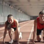 Transition Skills - Men and Woman in Red Tank Top is Ready to Run on Track Field