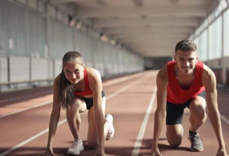 Transition Skills - Men and Woman in Red Tank Top is Ready to Run on Track Field