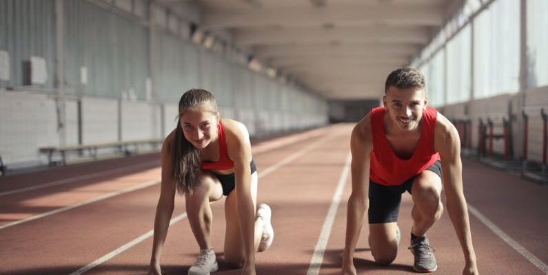 Transition Skills - Men and Woman in Red Tank Top is Ready to Run on Track Field