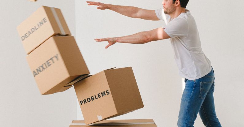 Hydrostatic Pressure - Full body of young man in sneakers and jeans pushing and falling boxes saying Work Problems Anxiety Stress and Deadline while fighting with problems